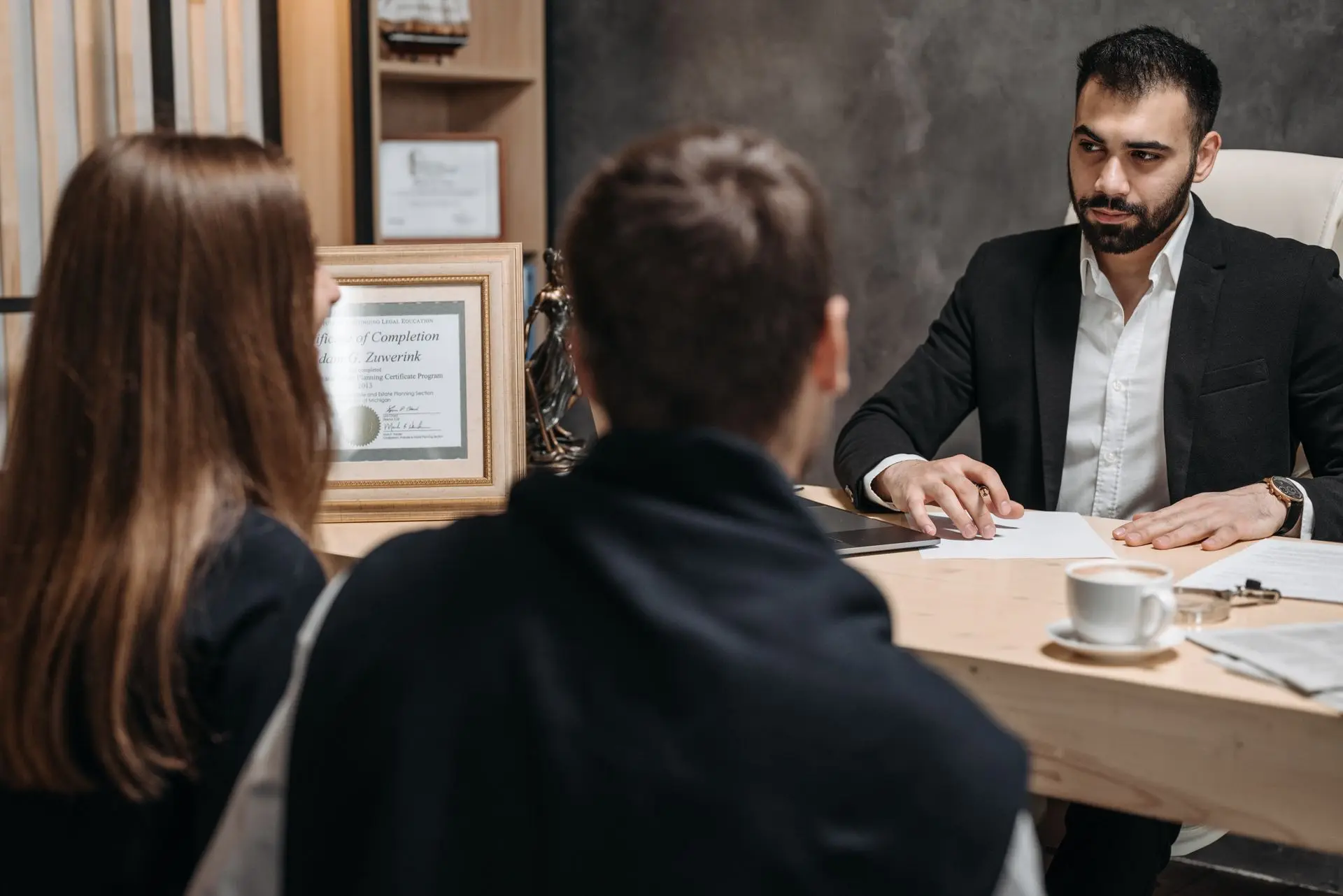 Abogado atendiendo a dos clientes en su escritorio durante una consulta legal